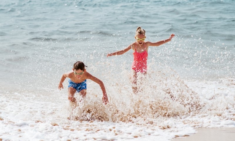 Nasmejani devojčica i dečak na peščanoj plaži